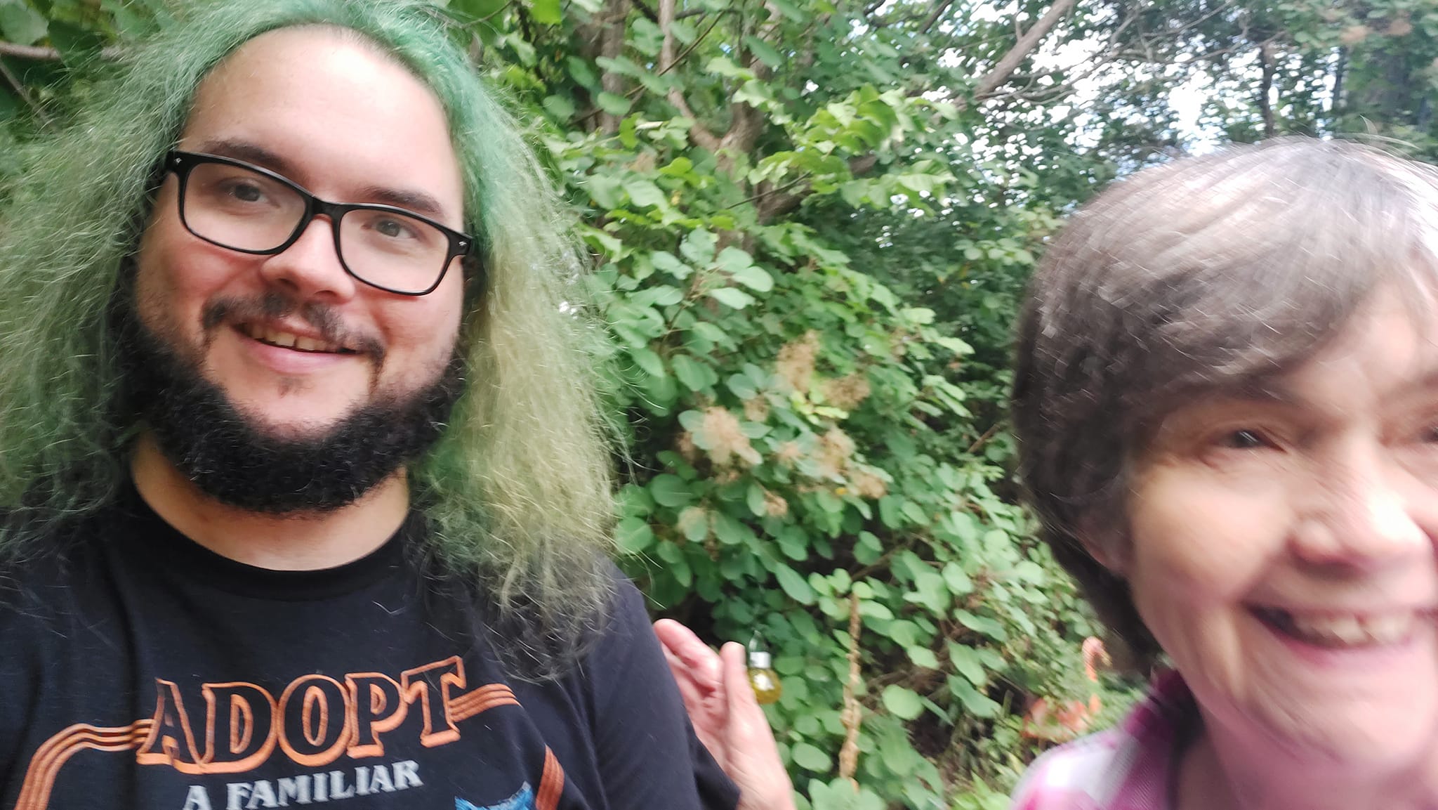 A man with green hair and a beard is outside with his mother